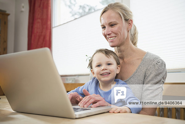 Mother and son using laptop  smiling