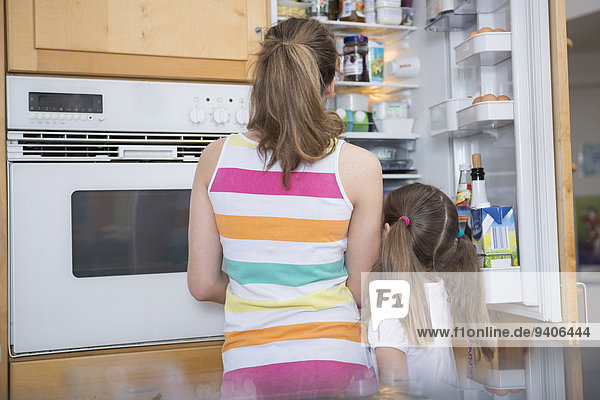 Sisters looking into refrigerator