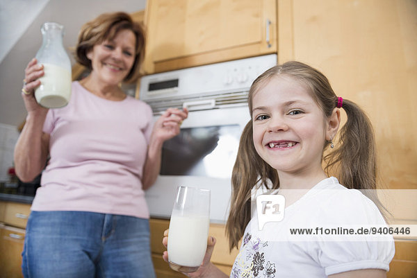 Grandmother and granddaughter holding glass of milk  smiling