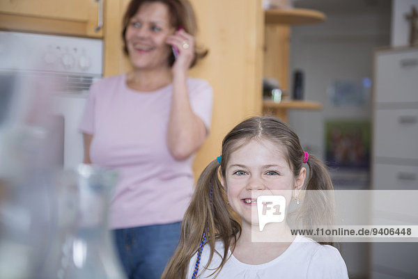 Portrait of girl with bunches while woman talking on phone  smiling