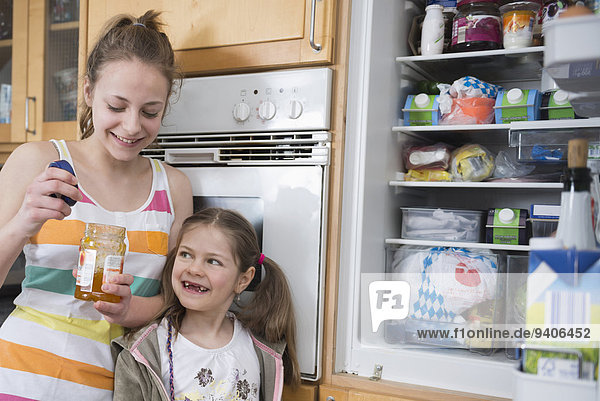Sisters looking into refrigerators  smiling