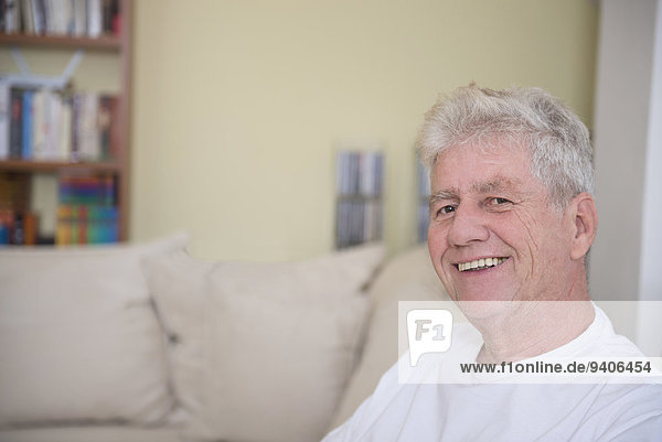 sitzend Senior Senioren Portrait Mann lächeln Couch