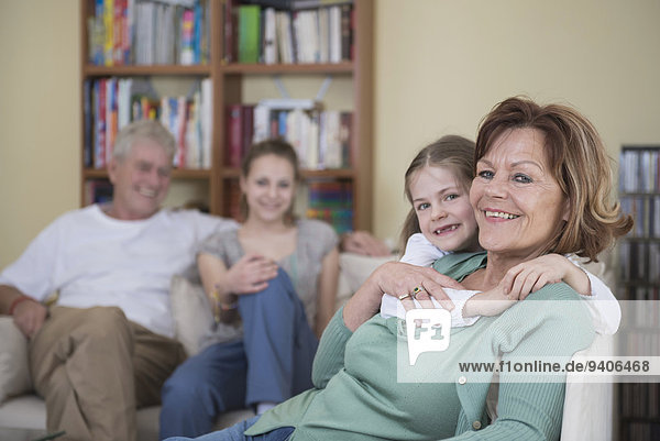 Portrait of grandparents and granddaughters sitting on couch  smiling
