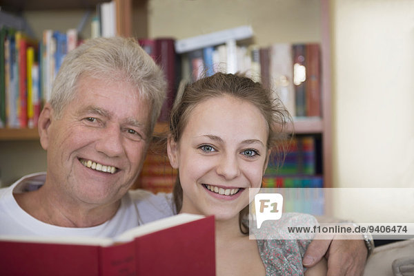 Buch lächeln Zimmer Enkeltochter Großvater Couch Taschenbuch Wohnzimmer vorlesen
