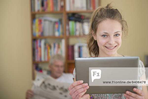 benutzen Portrait lächeln Zimmer Enkeltochter Großvater Tablet PC Wohnzimmer Zeitung vorlesen