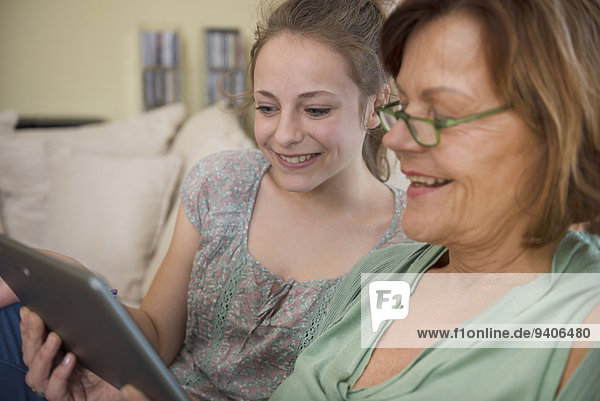 benutzen lächeln Zimmer Enkeltochter Großmutter Tablet PC Wohnzimmer