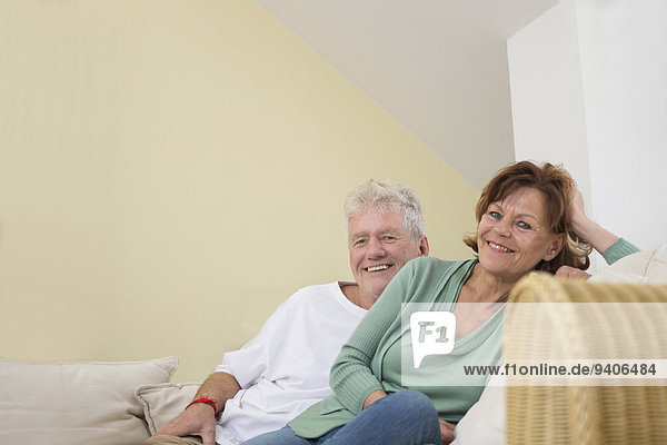 Portrait of senior couple sitting on couch in living room  smiling