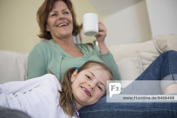 Grandmother and granddaughter on couch in living room  smiling