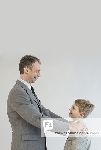 Father talking to son with hands on his shoulder  smiling