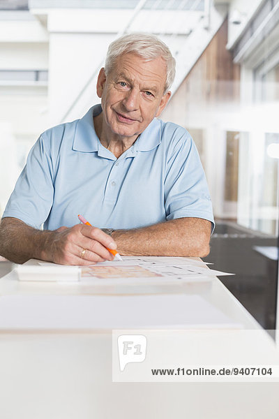 Senior man writing on document at home