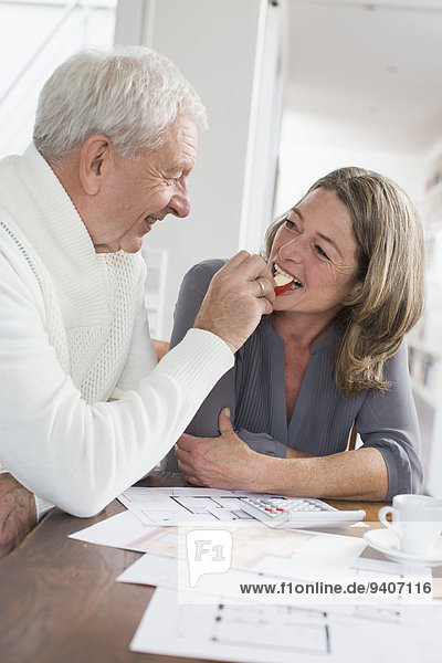Happy senior man feeding woman with apple slices