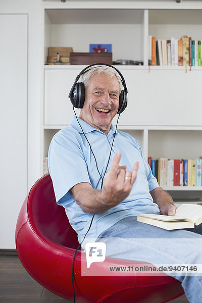 Senior man sitting in armchair listening to music