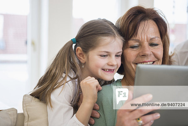 Grandmother and granddaughter looking in digital tablet  smiling