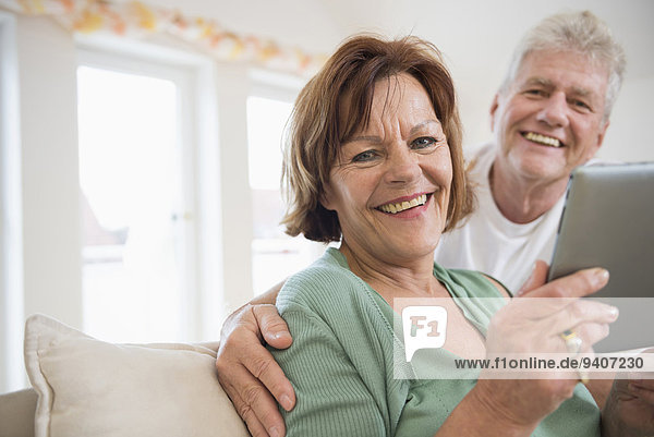 Portrait of senior couple with digital tablet  smiling