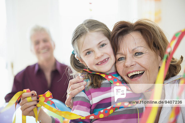 Family with blowout paper streamer at birthday party  smiling