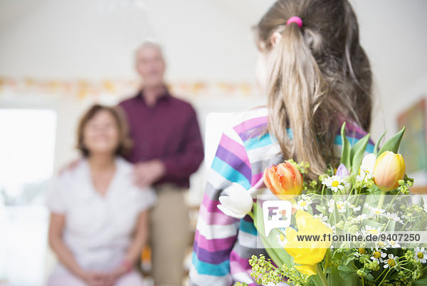 Granddaughter handover bouquet to her grandmother and grandfather in background