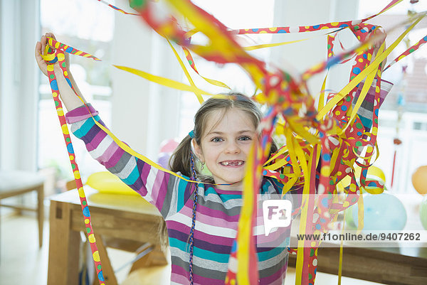 Portrait of girl with blowout paper streamer at birthday party  smiling