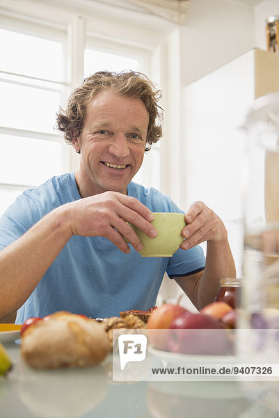 Smiling man sitting at breakfast table in kitchen