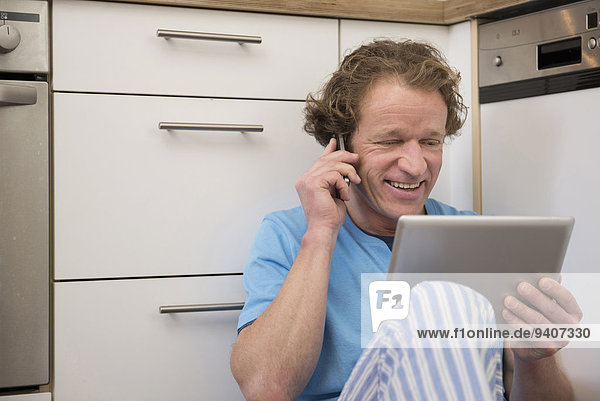 Handy benutzen Mann Schlafanzug Küche Tablet PC