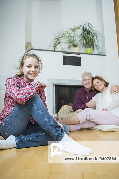 Granddaughter and grandparents sitting in front of fireplace  smiling