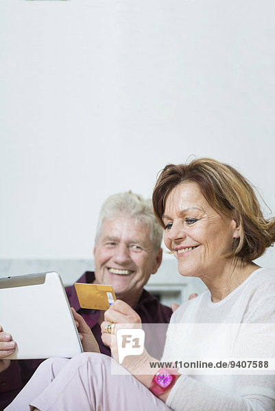 Senior couple doing internet shopping on digital tablet  smiling