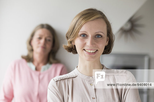 Smiling adult daughter with mother in background  portrait