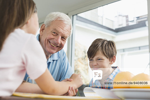 Children doing homework with their grandfather