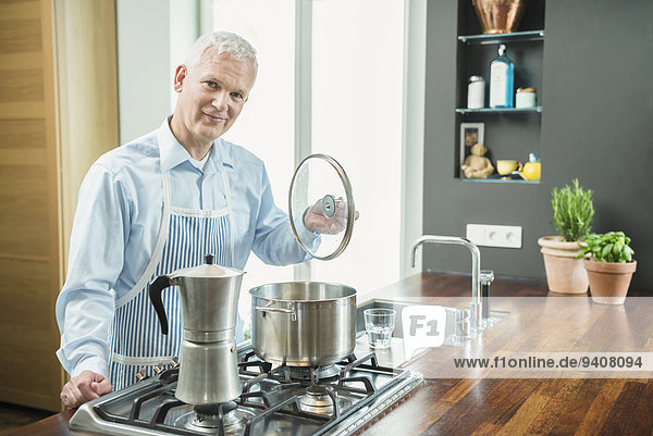 Portrait of mature man preparing food in kitchen  smiling