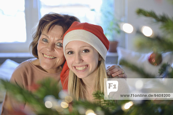 Grandmother and granddaughter in front of christmas tree  smiling  portrait