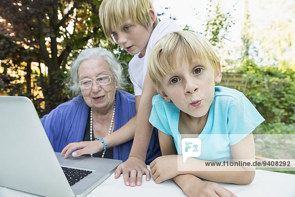 Grandmother and her two grandsons with laptop