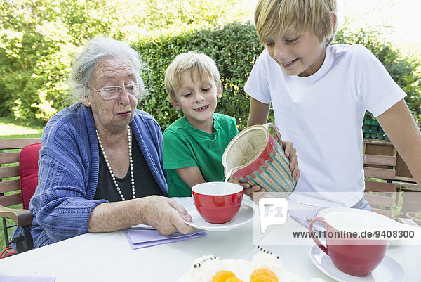 Tasse eingießen einschenken Enkelsohn Großmutter Milch