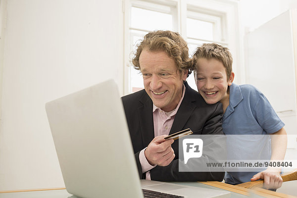Father and son with laptop and credit card