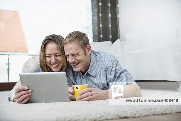 Couple lying on floor with digital tablet