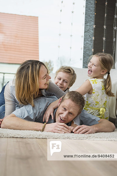 Happy family with two kids at home  lying on floor