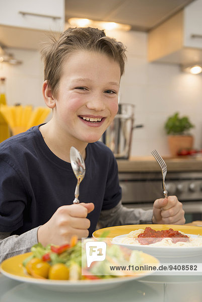 Smiling boy eating spaghetti and salad