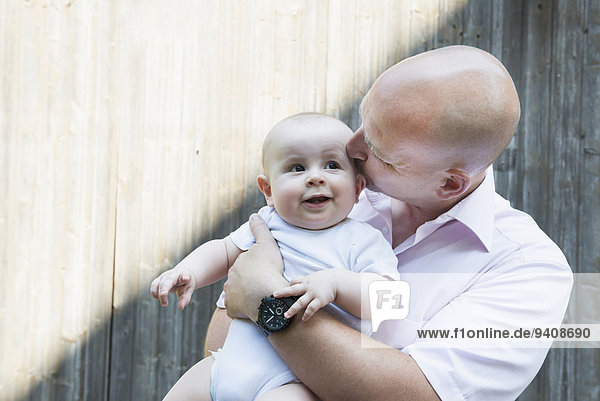 Stolz lächeln Menschlicher Vater Sohn küssen halten Baby