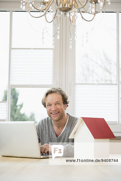Man with architectural model and laptop at table