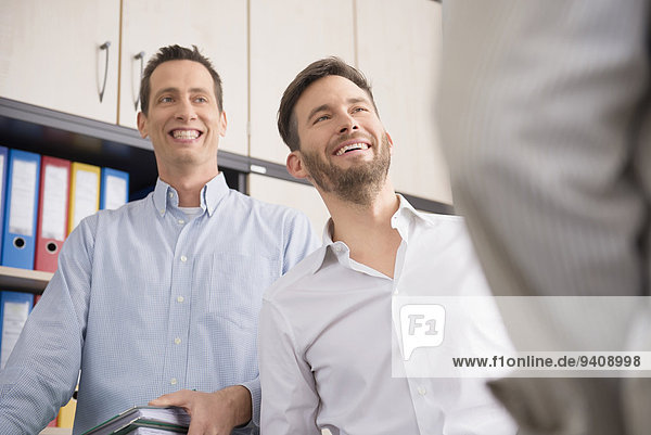 Three men office talking smiling working