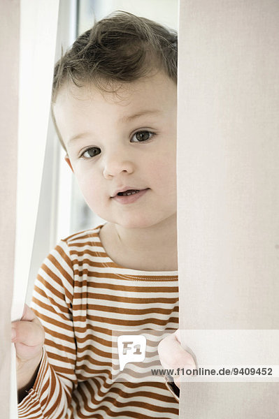 Portrait of boy playing with curtain