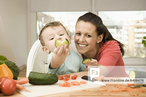 Mother and son preparing vegetables in kitchen  smiling