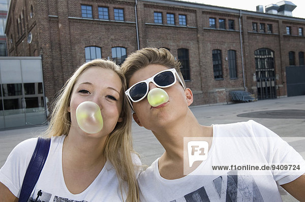 Teenage couple blowing bubble gum