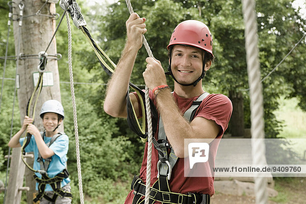Portrait of young man and boy climbing crag  smiling