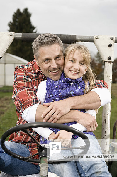 Farmer hugging daughter on tractor
