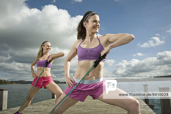 Women exercising on jetty with resistance band  Woerthsee