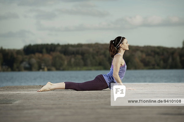 Woman practicing yoga on jetty  Woerthsee