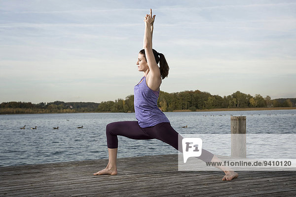 Woman practicing yoga on jetty  Woerthsee