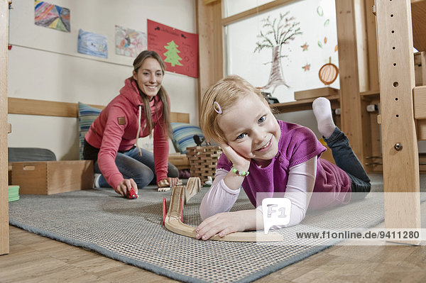 Little girl playing with wooden railroad in her kindergarten