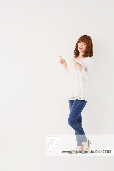 Full length portrait of young Japanese woman against white background