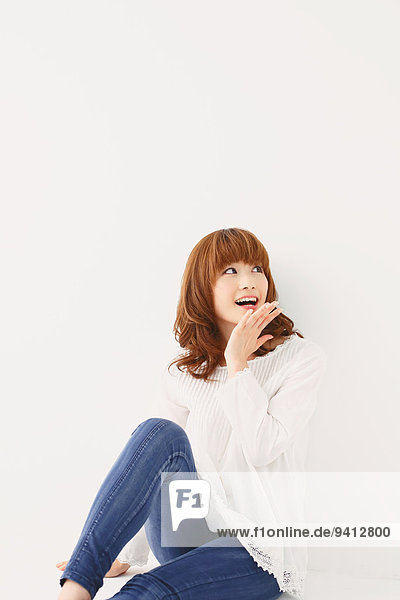 Half length portrait of young Japanese woman against white background
