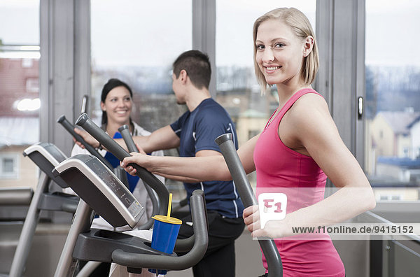 Young woman on elliptical trainer in gym